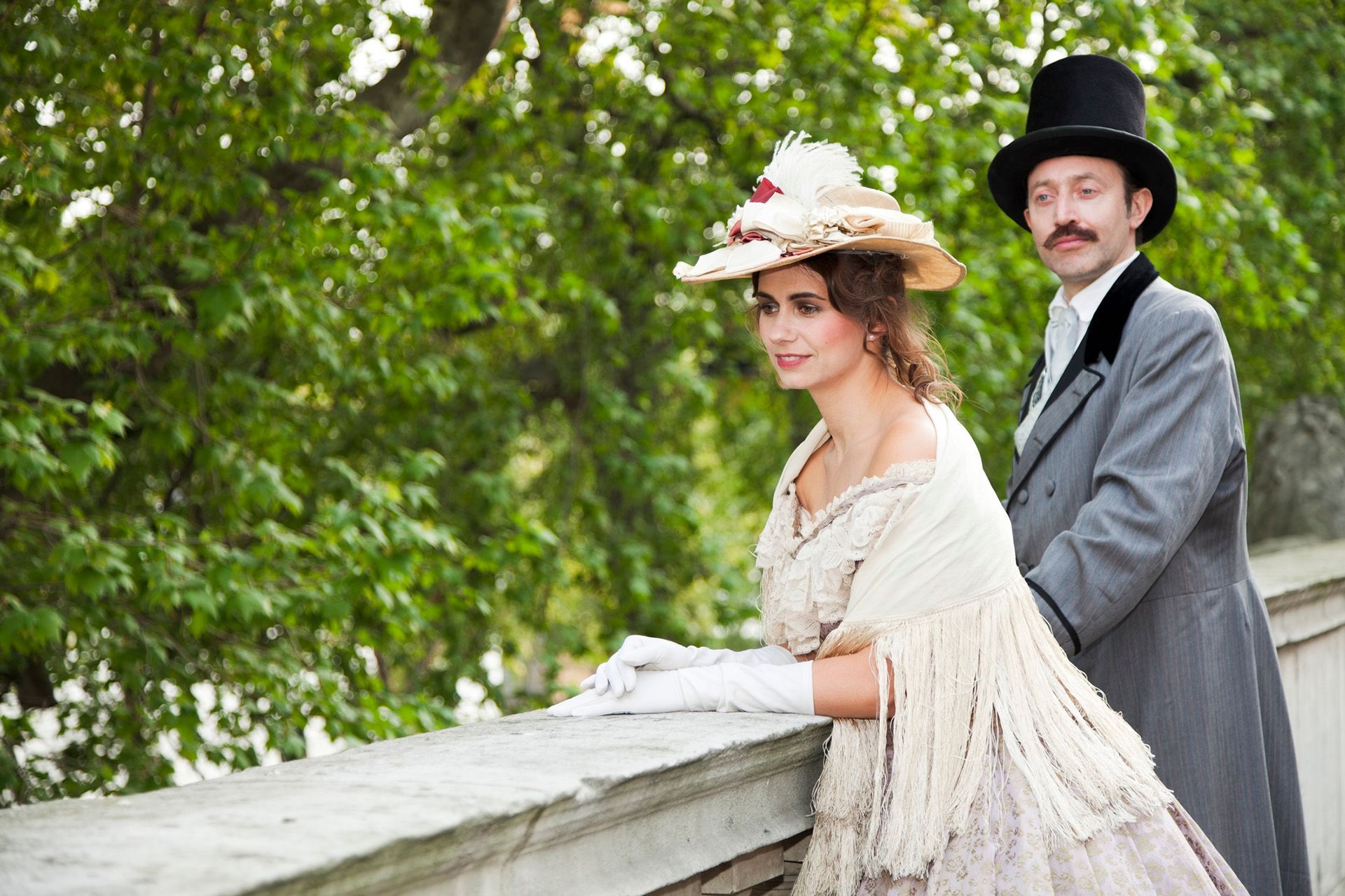 A man in a top hat and a woman in a dress are standing next to each other.