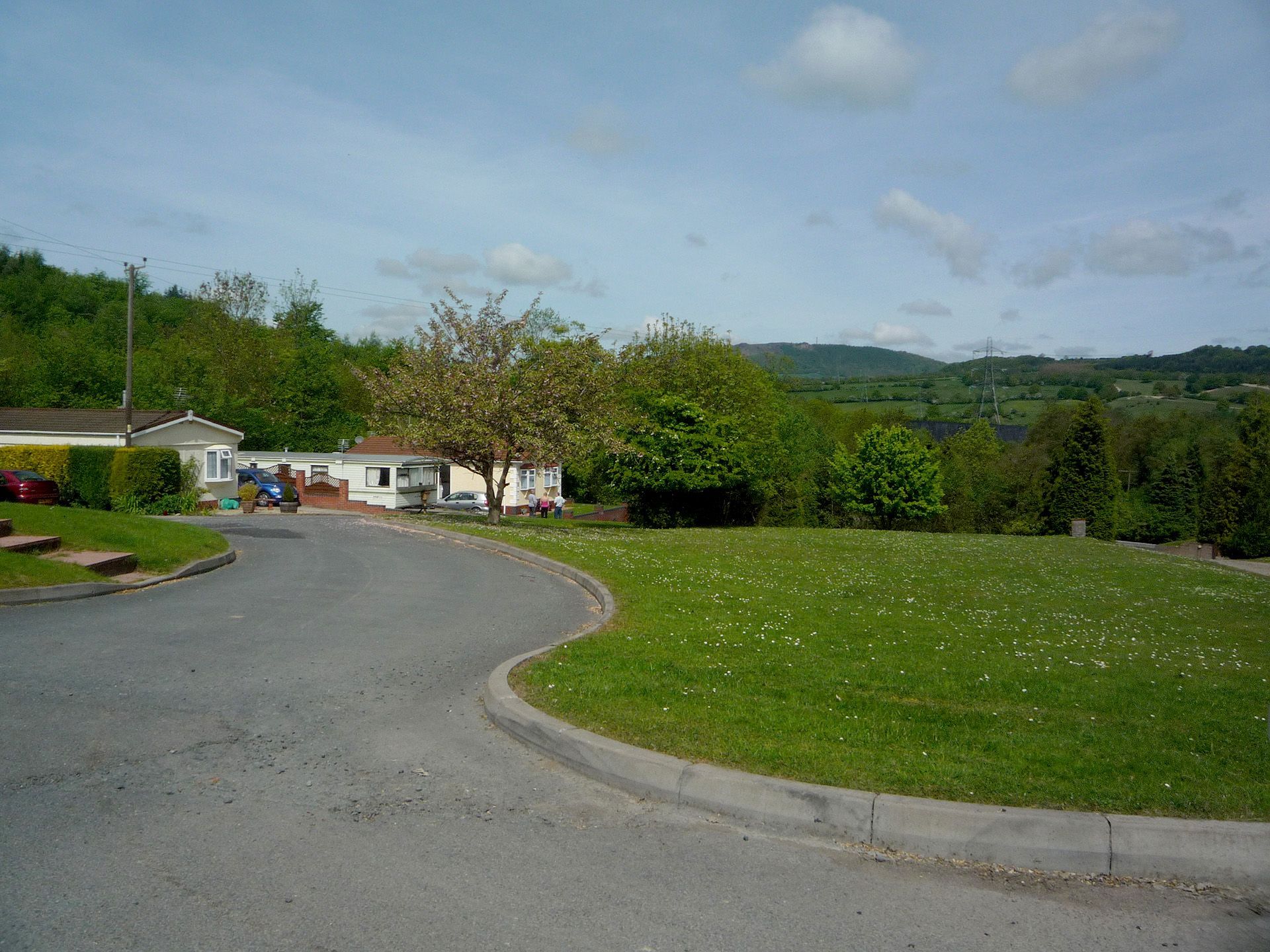 A road going through a grassy field with a house in the background