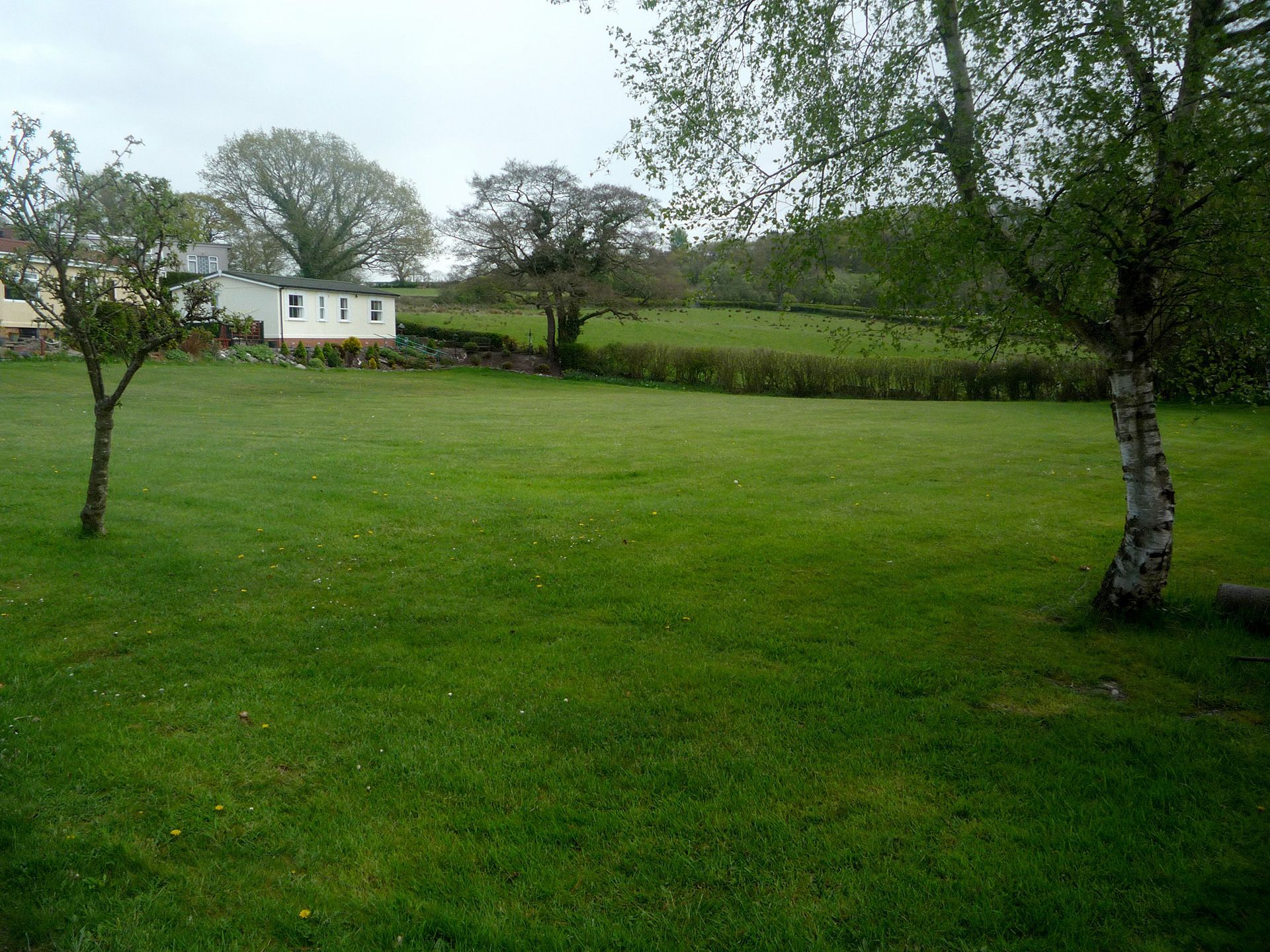 A mobile home with a large deck is sitting on the side of a road.