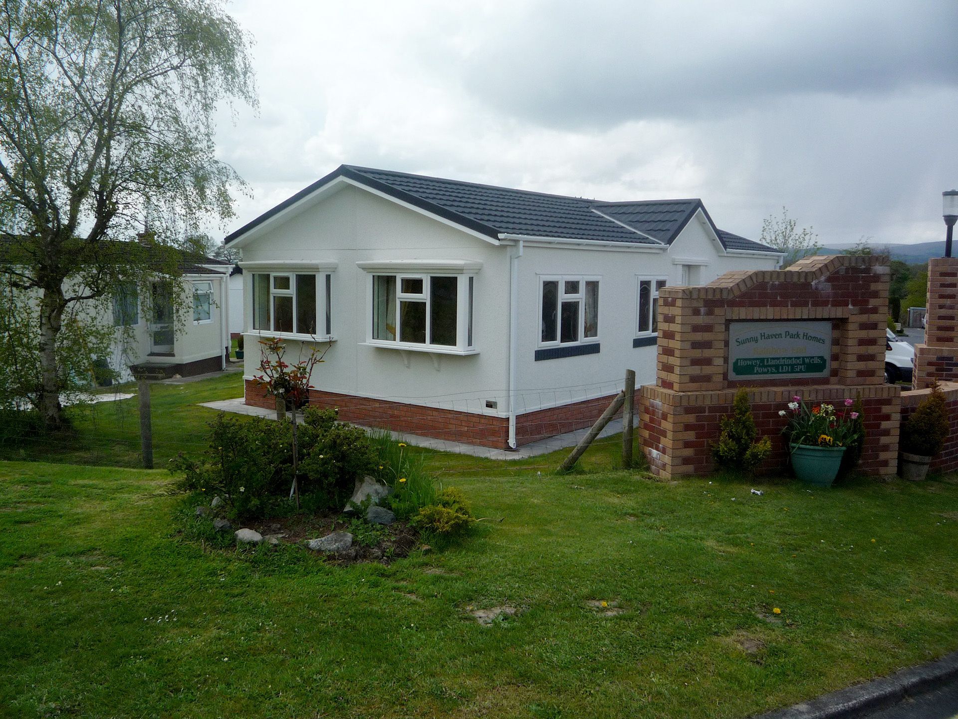 A white house with a black roof is surrounded by a lush green lawn.