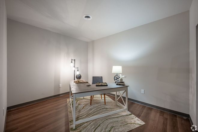 A room with a desk , chair , lamp and rug.