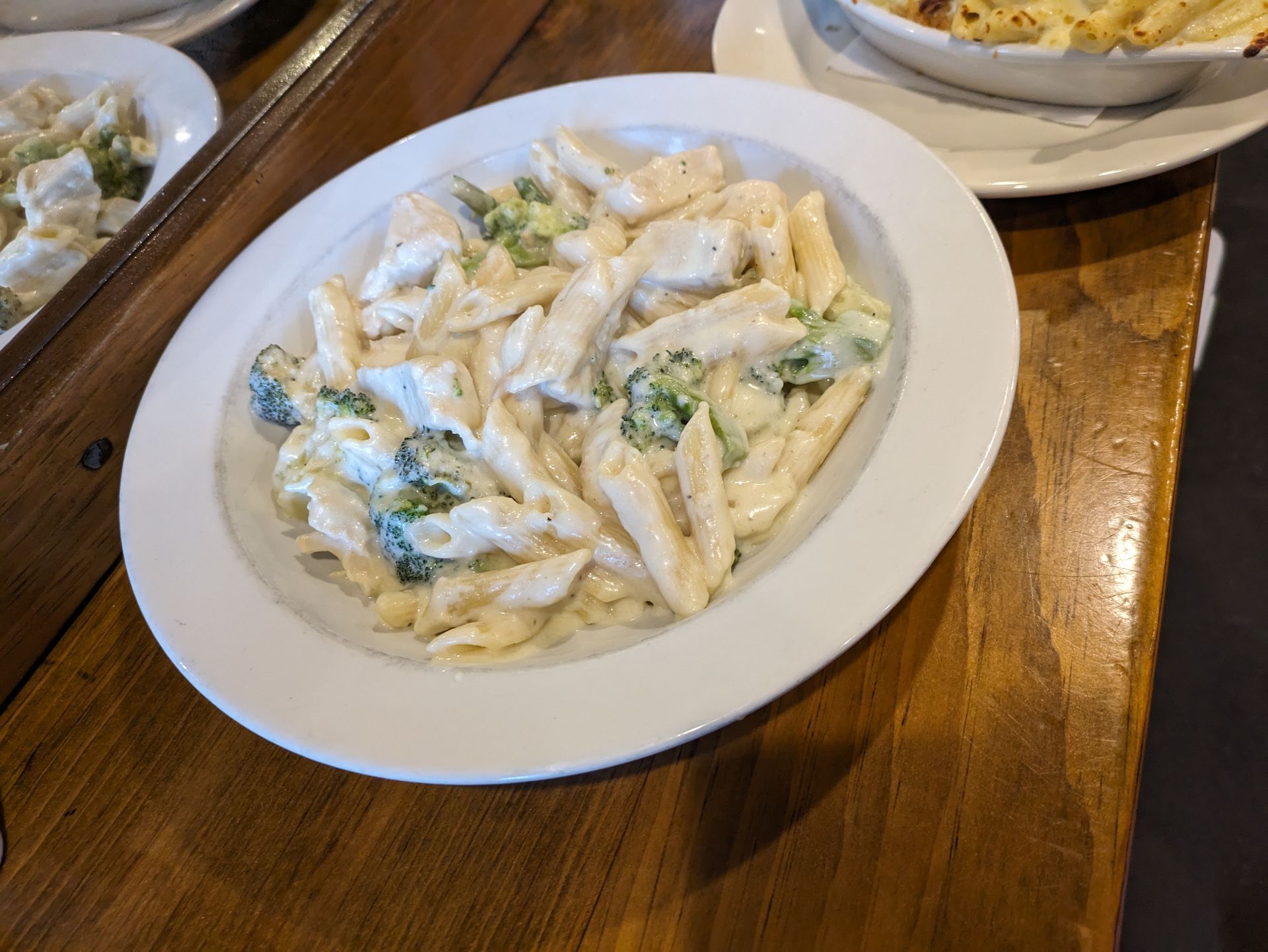 A white plate topped with pasta and broccoli on a wooden table.