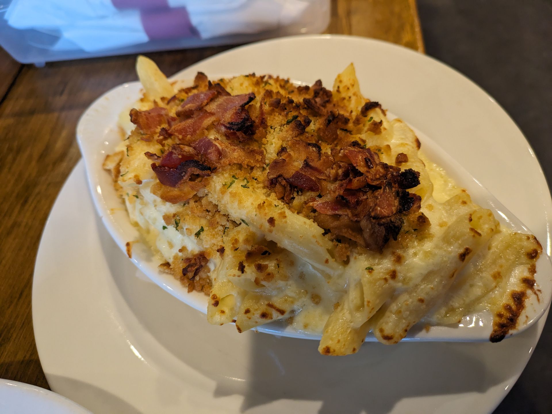 A white plate topped with macaroni and cheese and bacon.