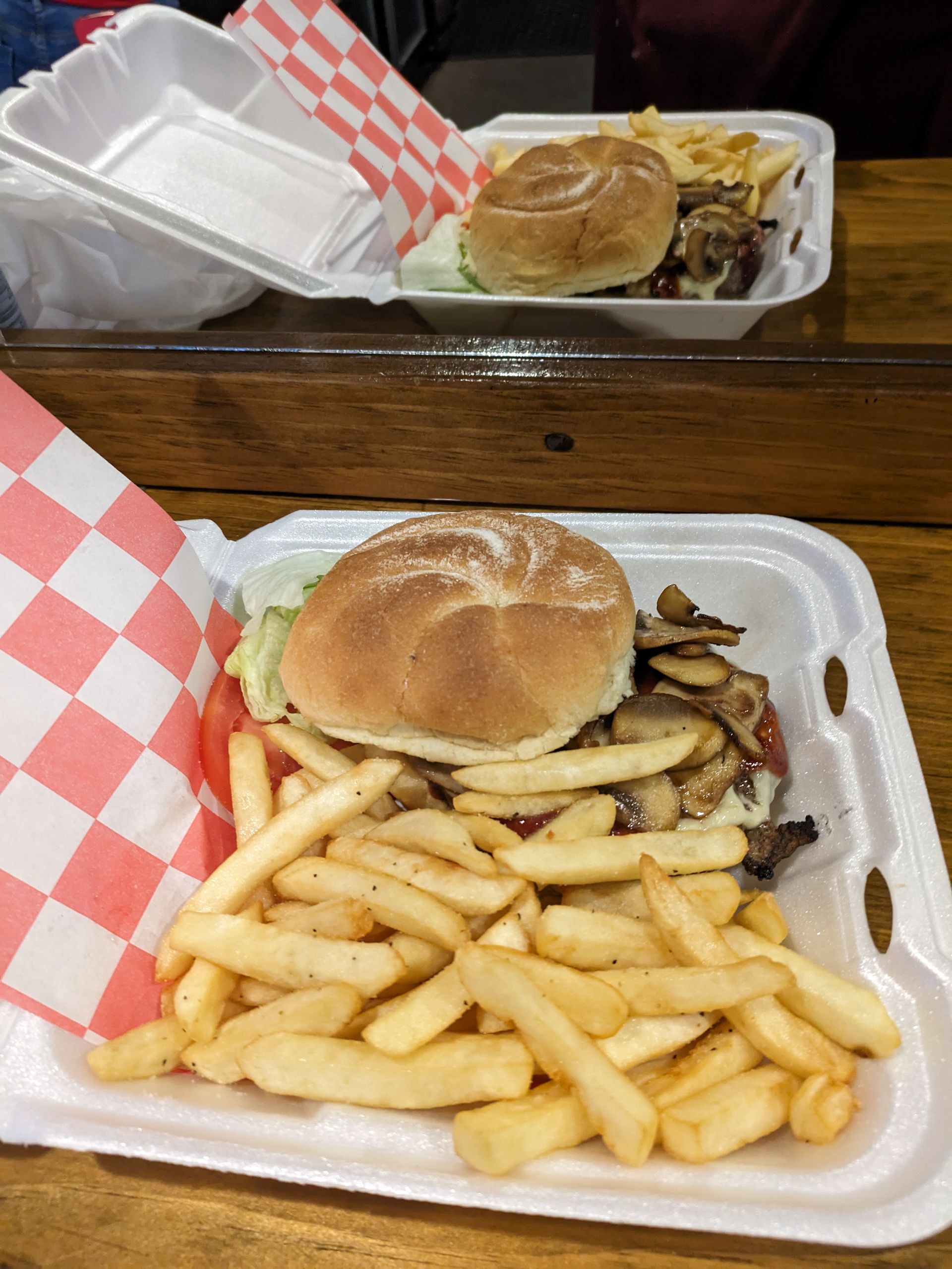 A hamburger and french fries in a styrofoam container