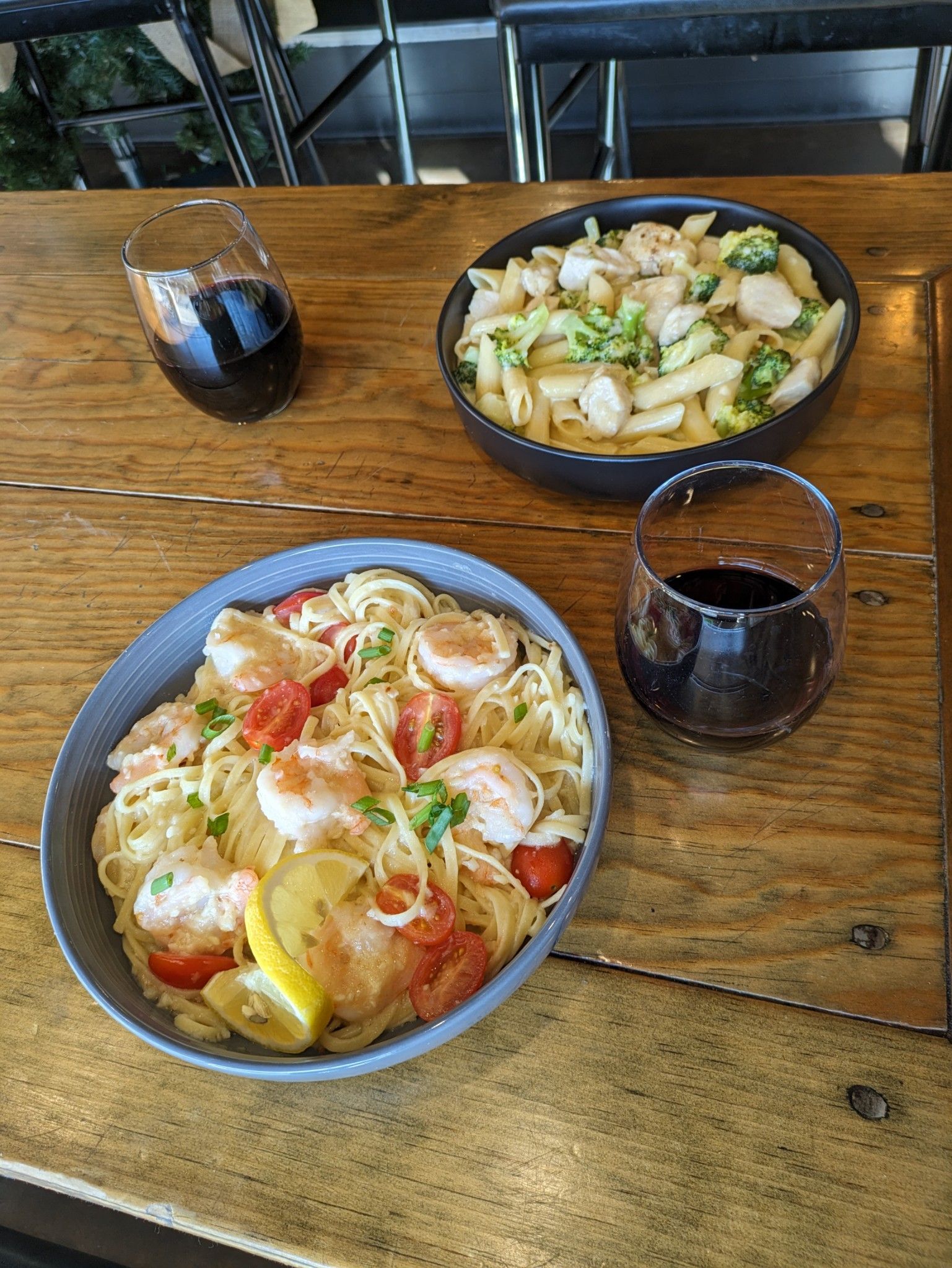 A wooden table topped with two bowls of food and a glass of wine.