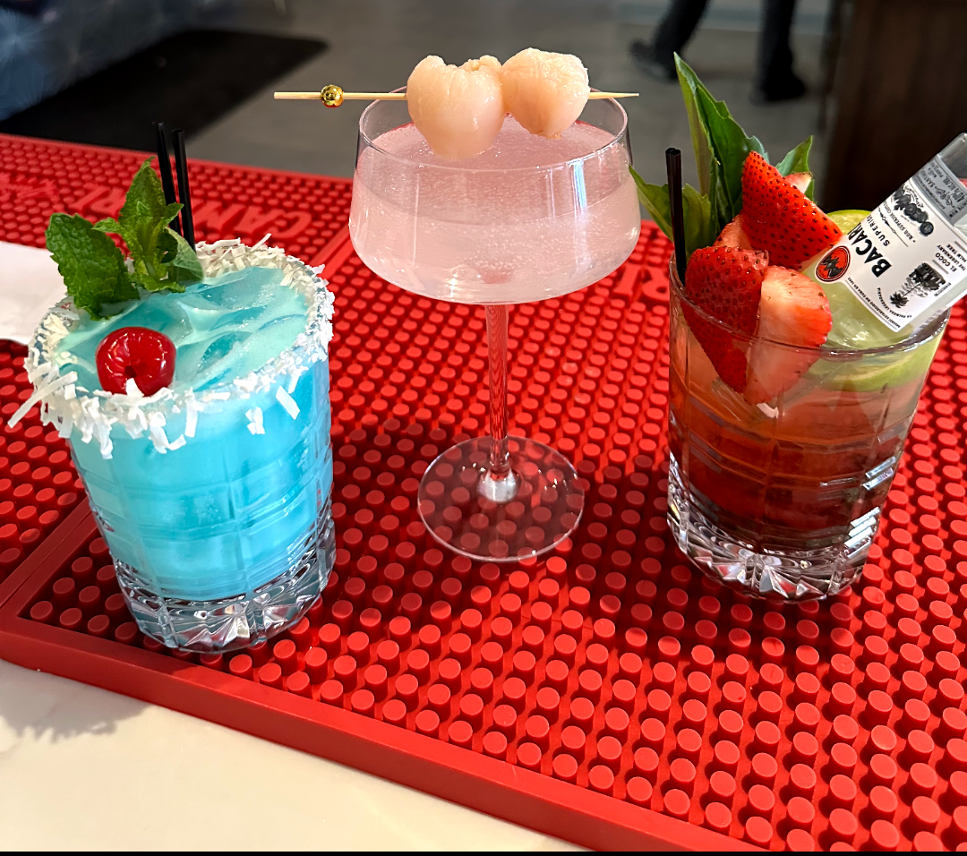 Three different cocktails are on a red mat on a table