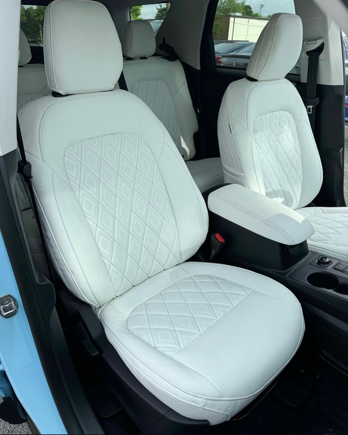 The interior of a car with white seats and a blue door.