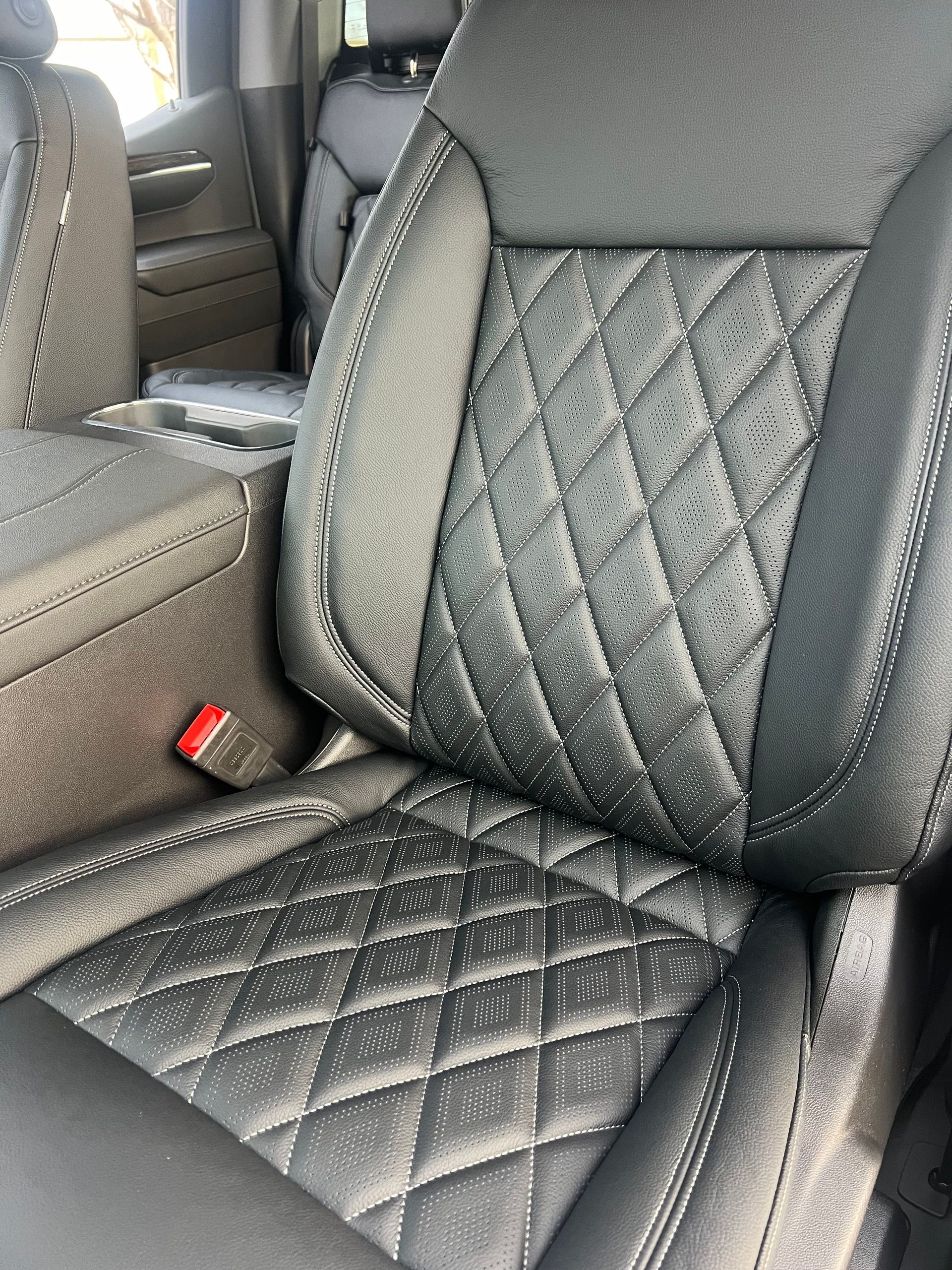 A close up of a black leather seat in a car.