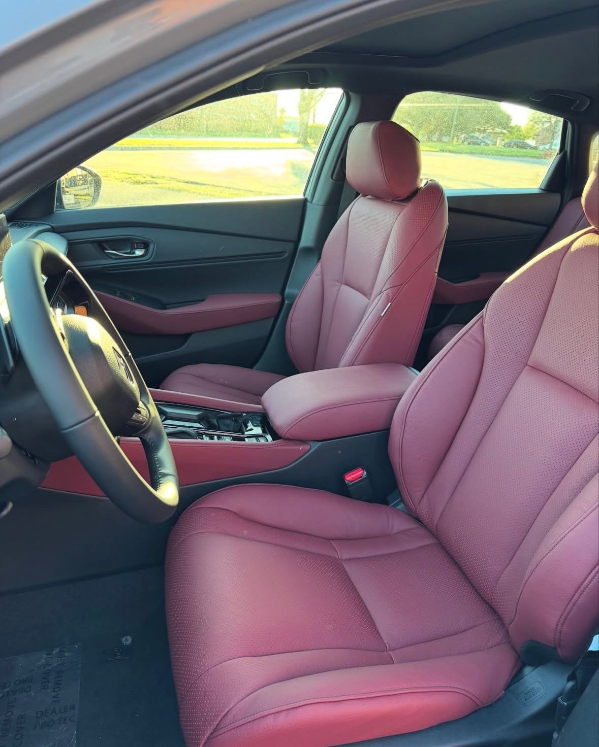 The inside of a car with red seats and a steering wheel.