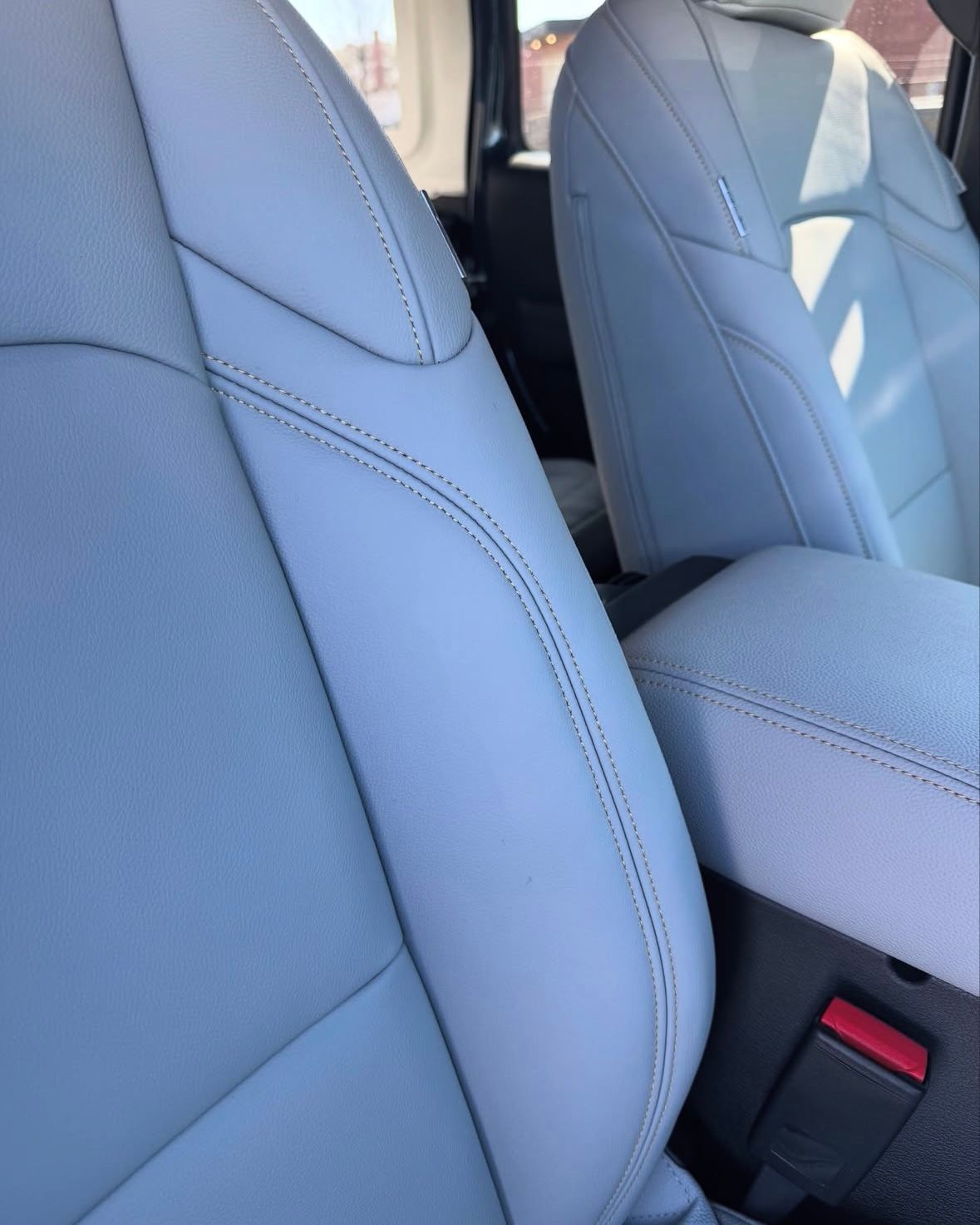 A close up of a car seat with a red buckle