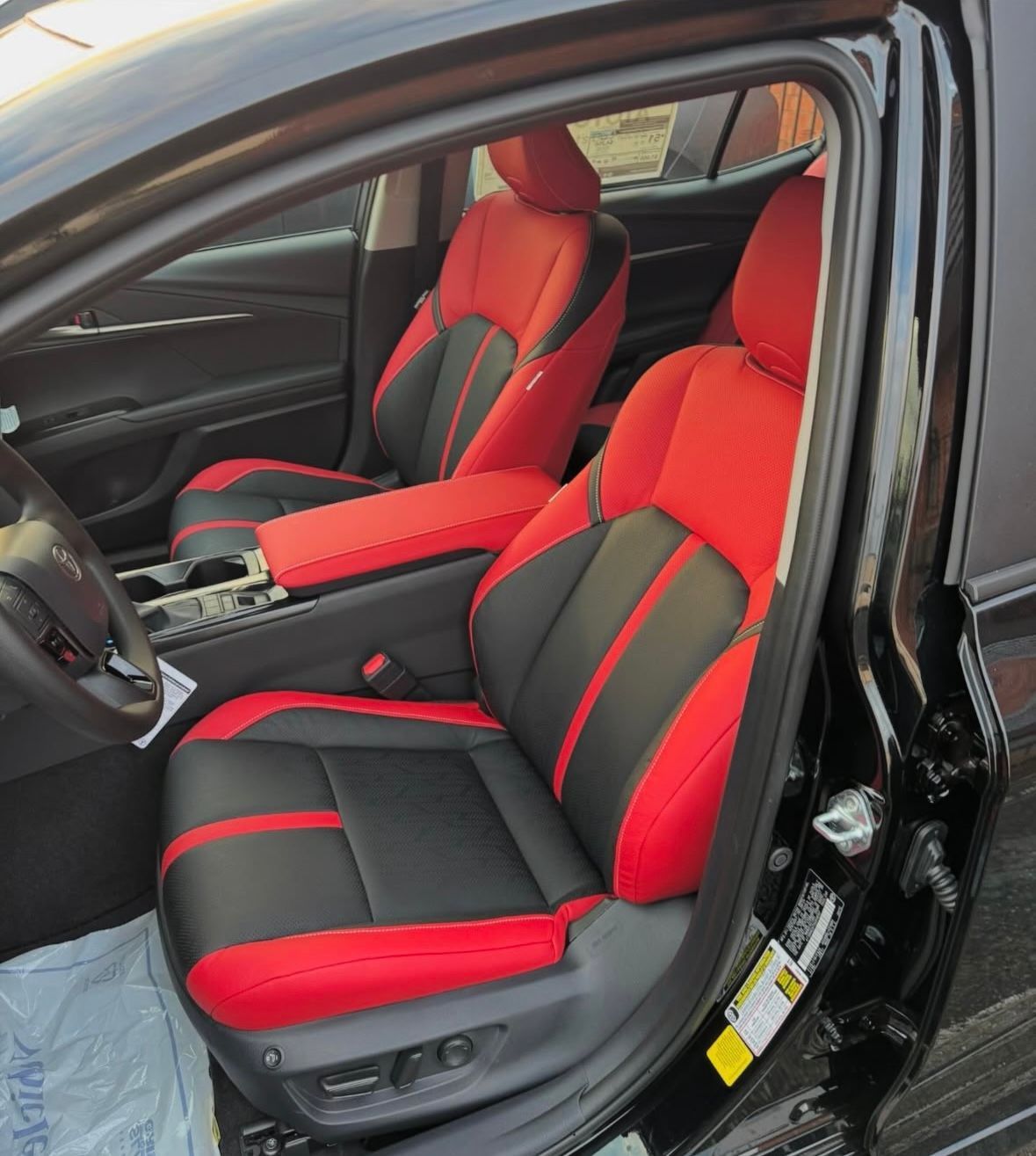 The inside of a black car with red and black seats
