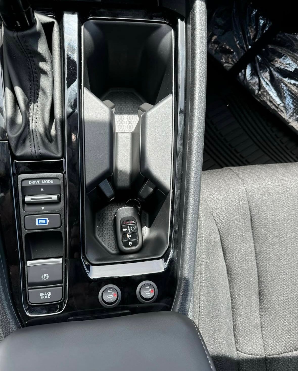 A close up of a car dashboard with a cup holder and a remote control.