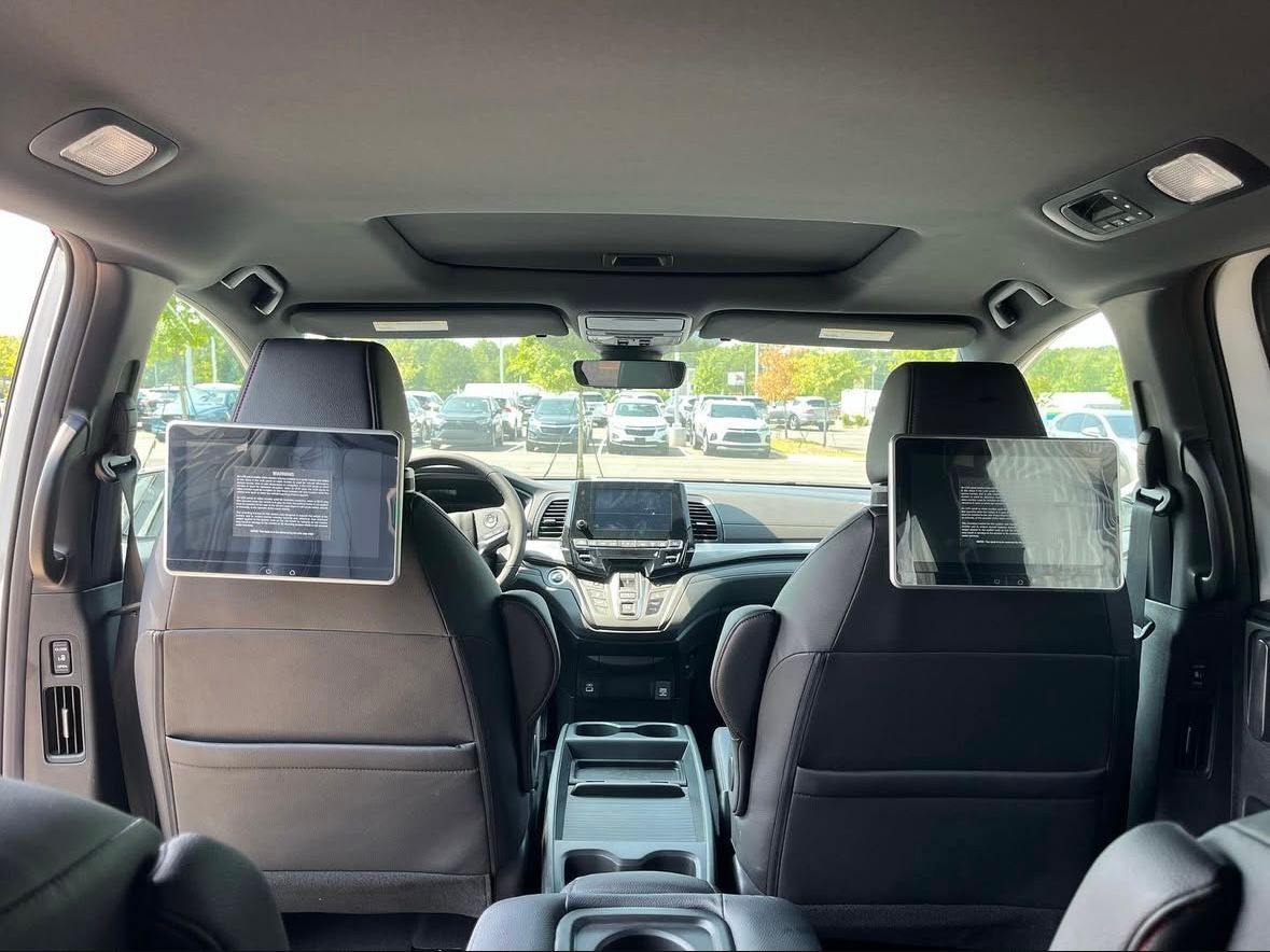 The interior of a minivan with a tablet mounted on the back seat.