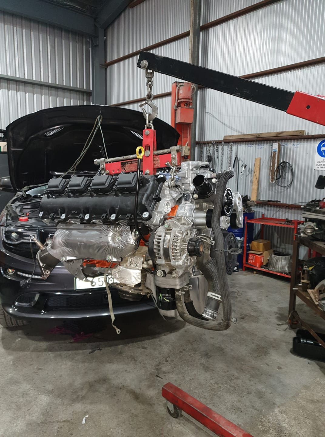 A Car Engine Is Being Lifted By A Crane In A Garage — Fulgi’s South Coast Automotive and Dismantling in Nowra, NSW