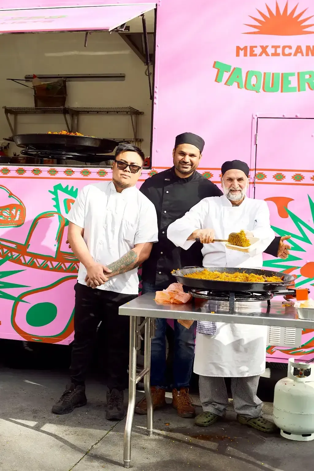 Three men are standing in front of a pink food truck by Maria's Mexican Food Truck.