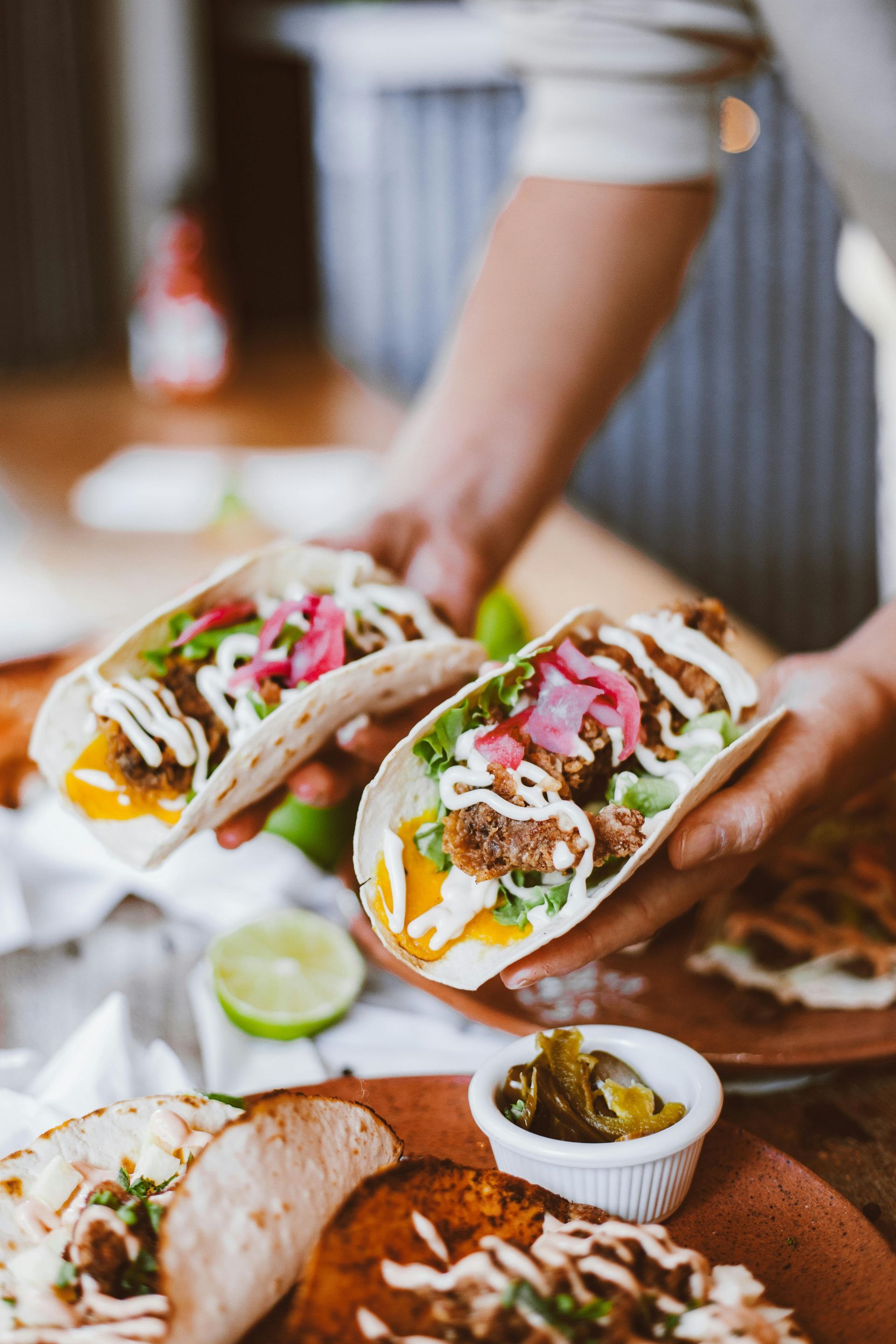 A person is holding two tacos in their hands.