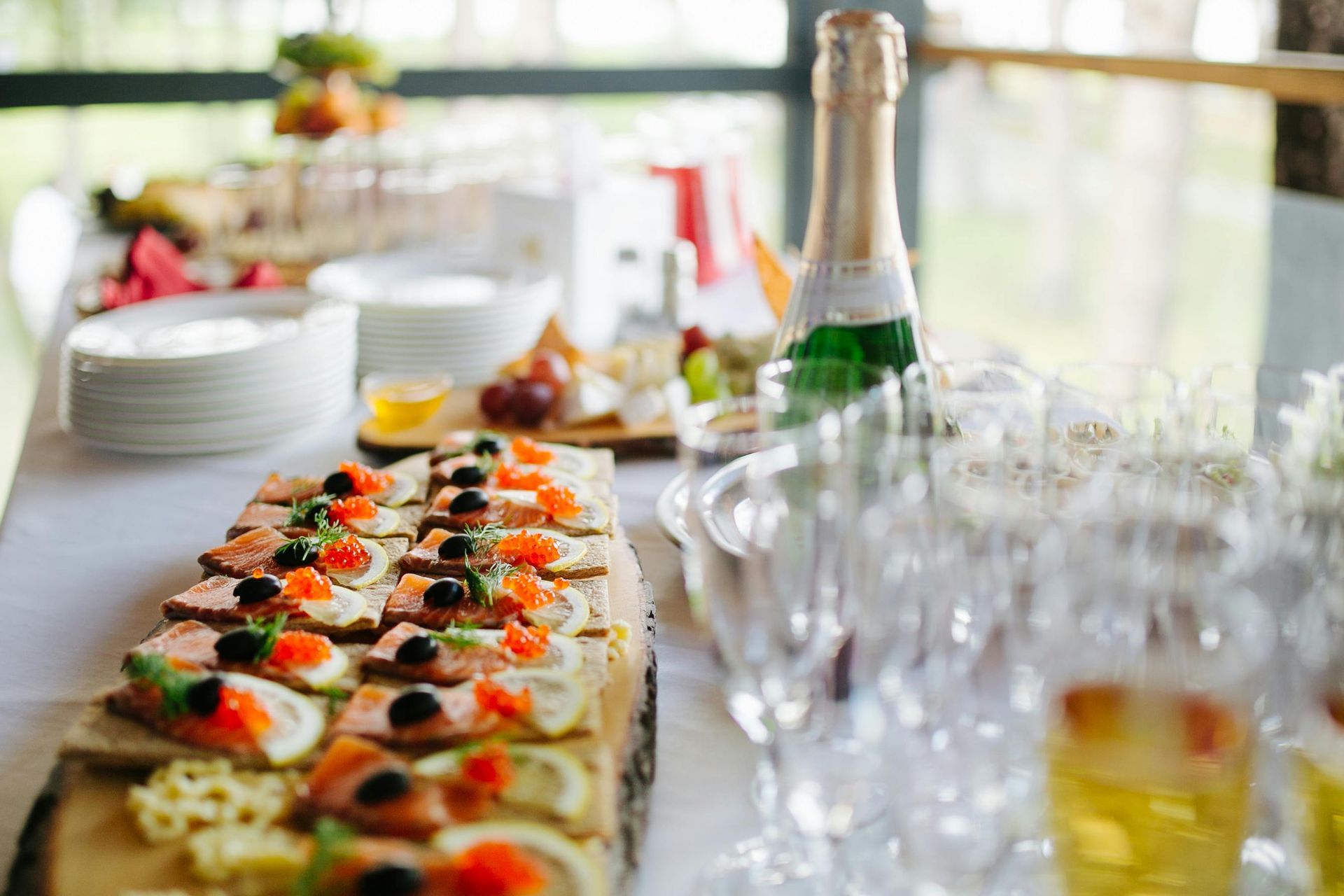 A buffet table with a bottle of champagne and glasses of wine for a wedding catering service in Melbourne.
