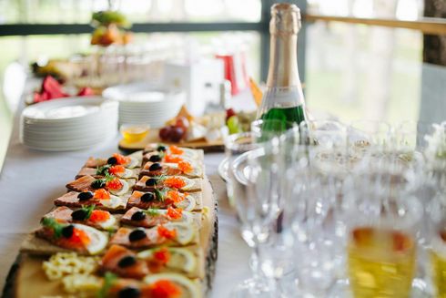 A buffet table with a bottle of champagne and glasses of wine.