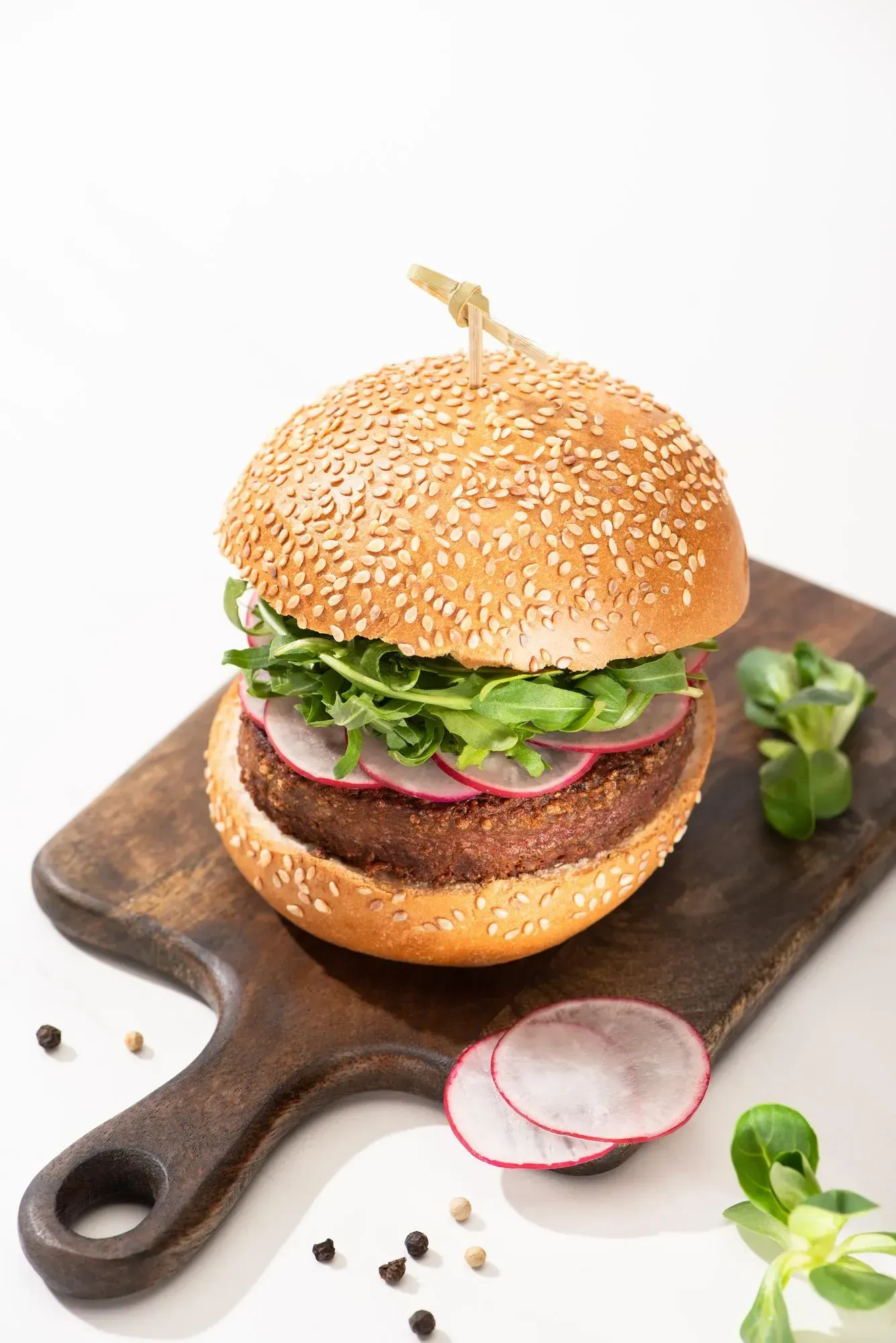 A vegetarian hamburger is sitting on a wooden cutting board.
