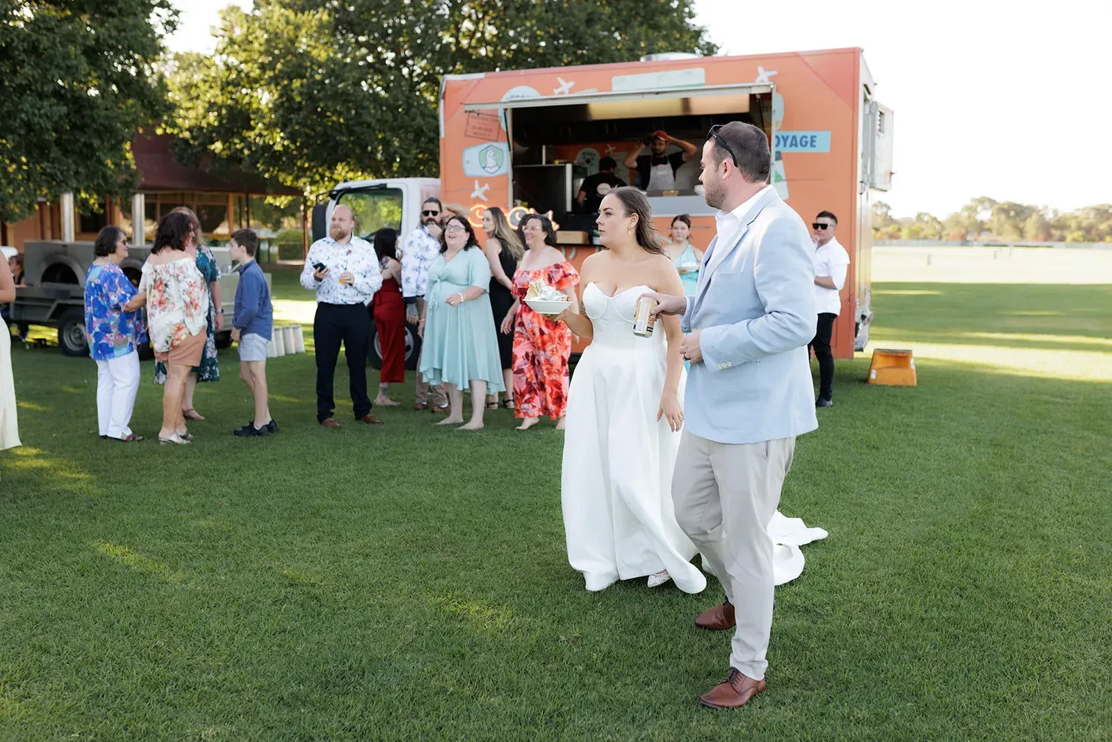 A bride and groom are walking in front of a food truck in Melbourne.