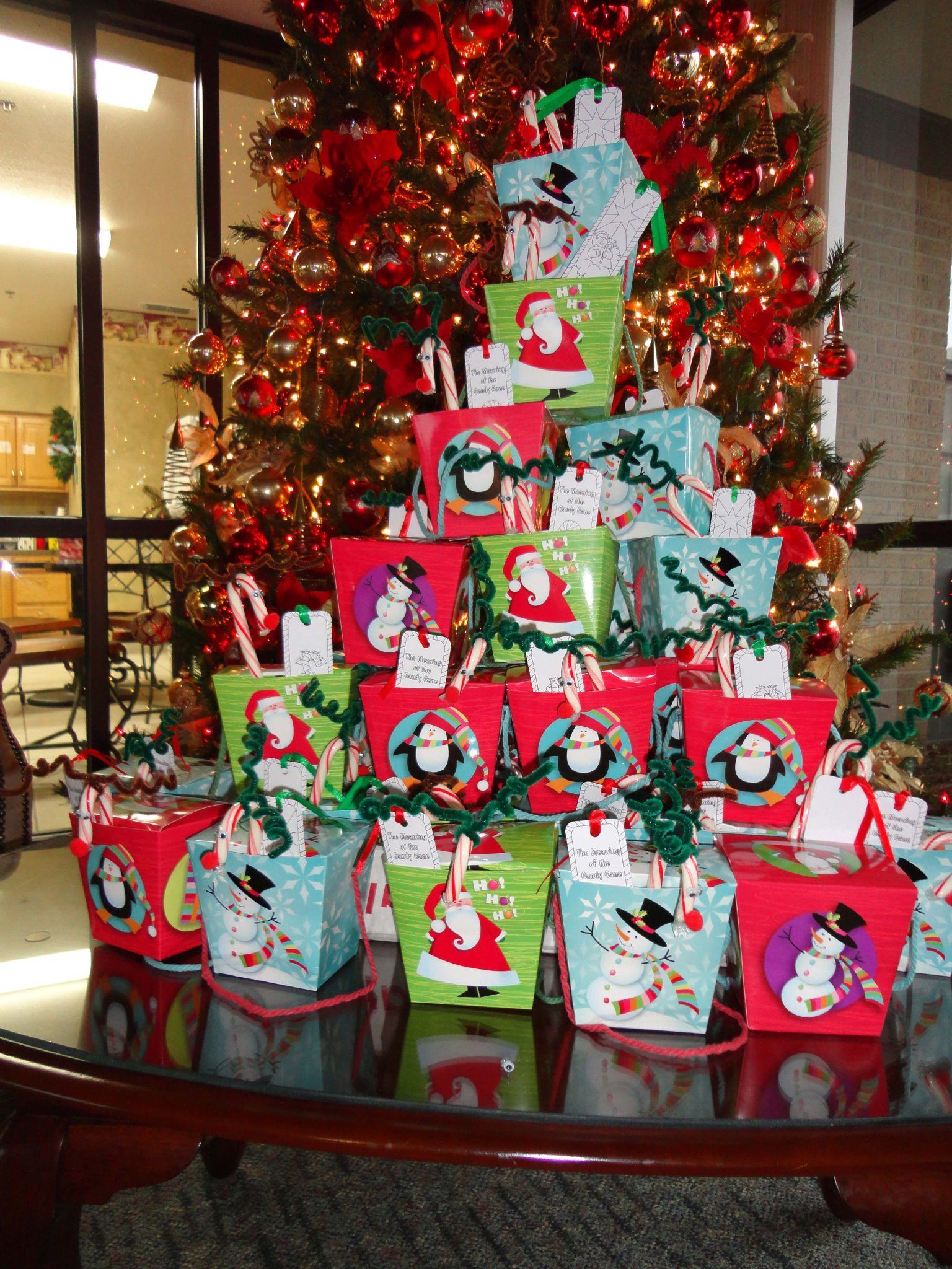 Christmas gift boxes stacked in front of a decorated tree, with Santa and snowman designs.