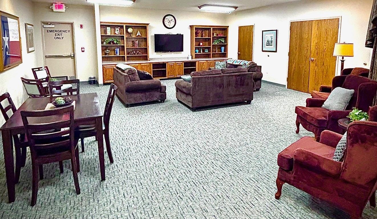 Living room with brown furniture, a TV, bookshelves, and dining table.