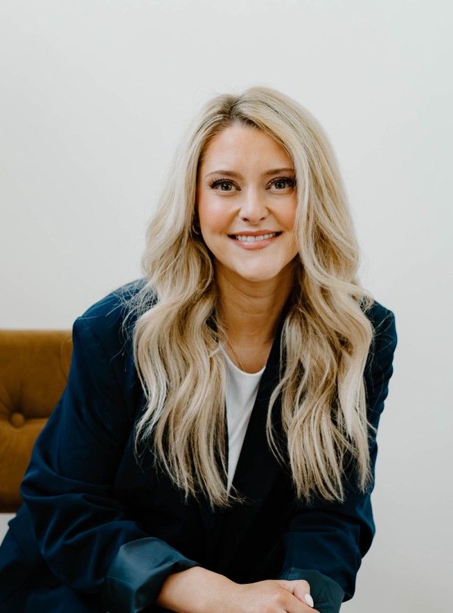 A woman in a red dress is smiling with her arms crossed