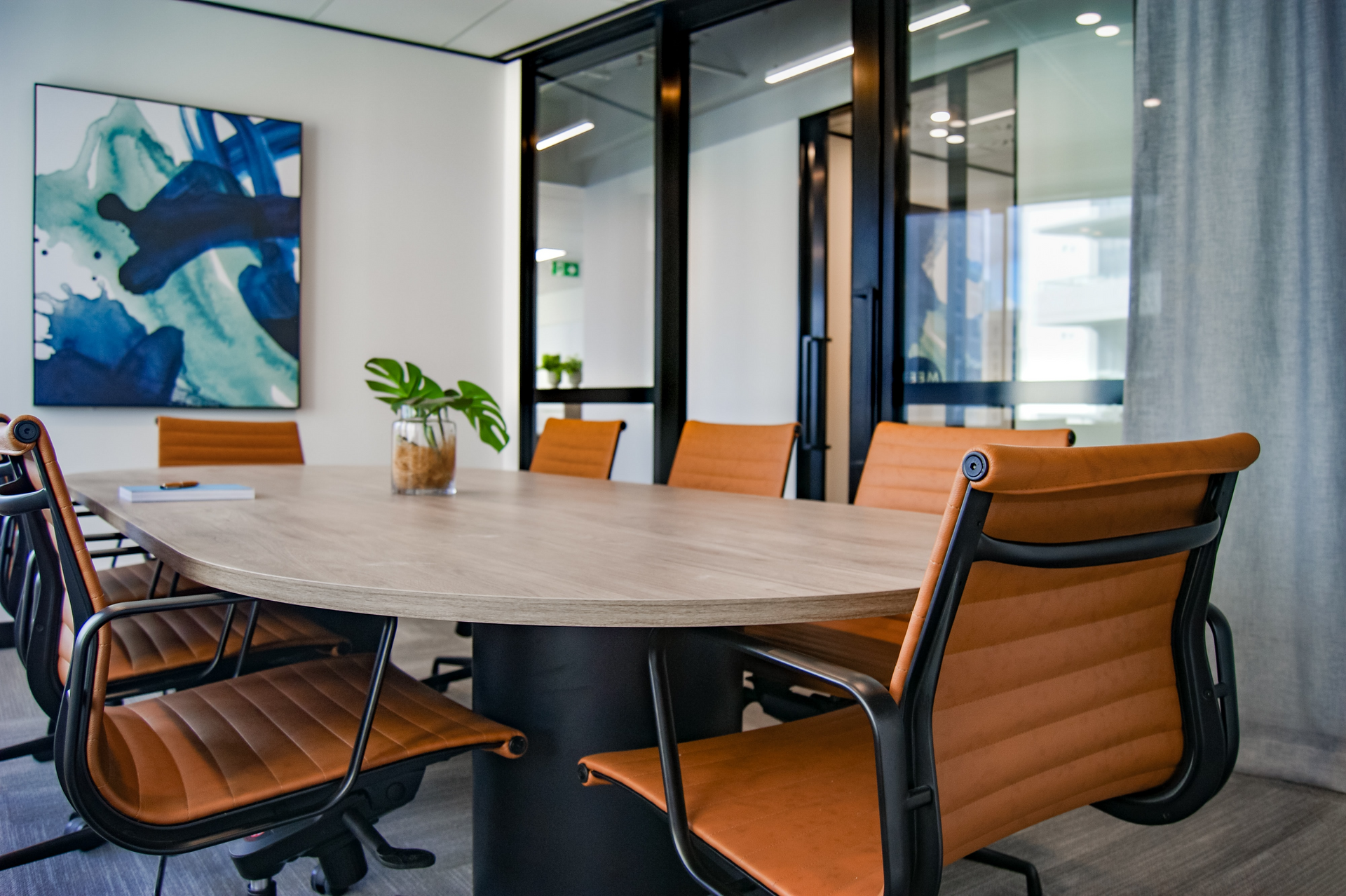 A conference room with a table and chairs and a painting on the wall.