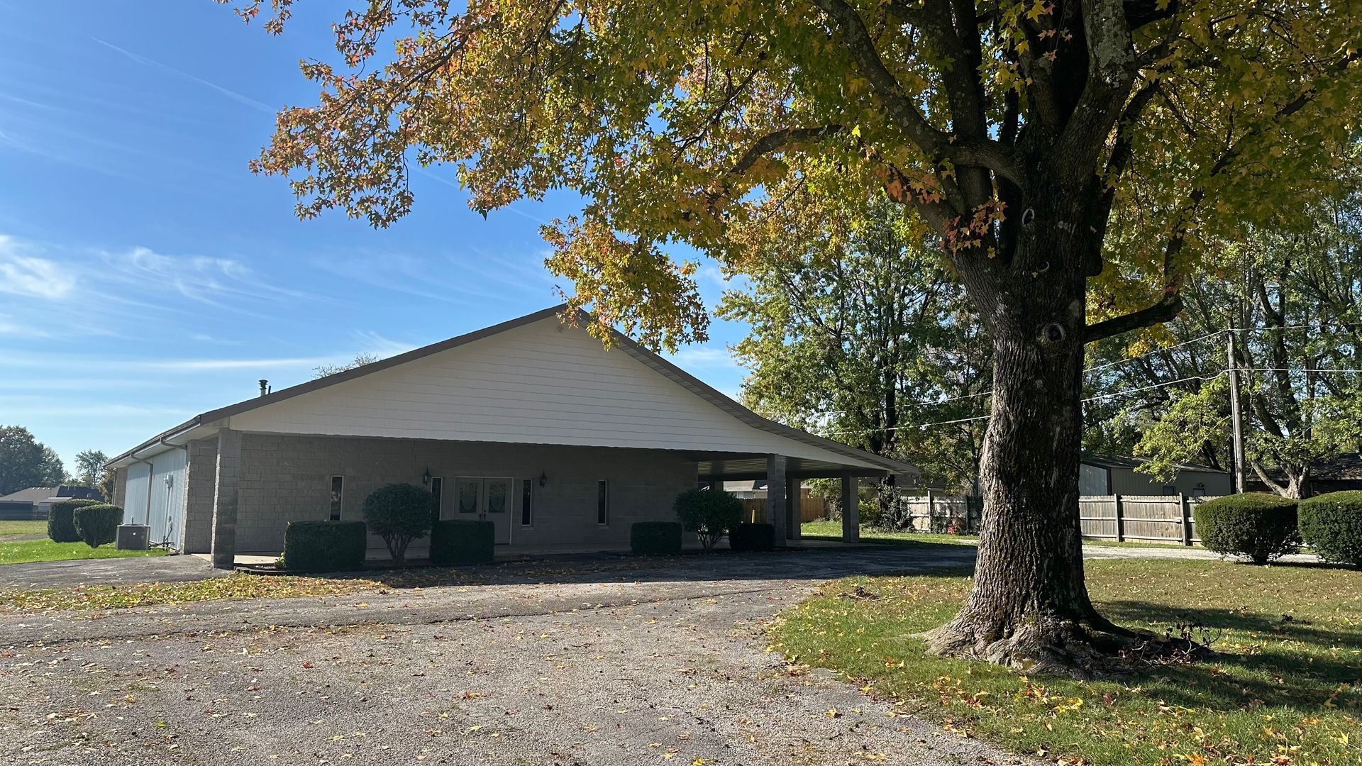 A dirt road leading into a field surrounded by fall trees.