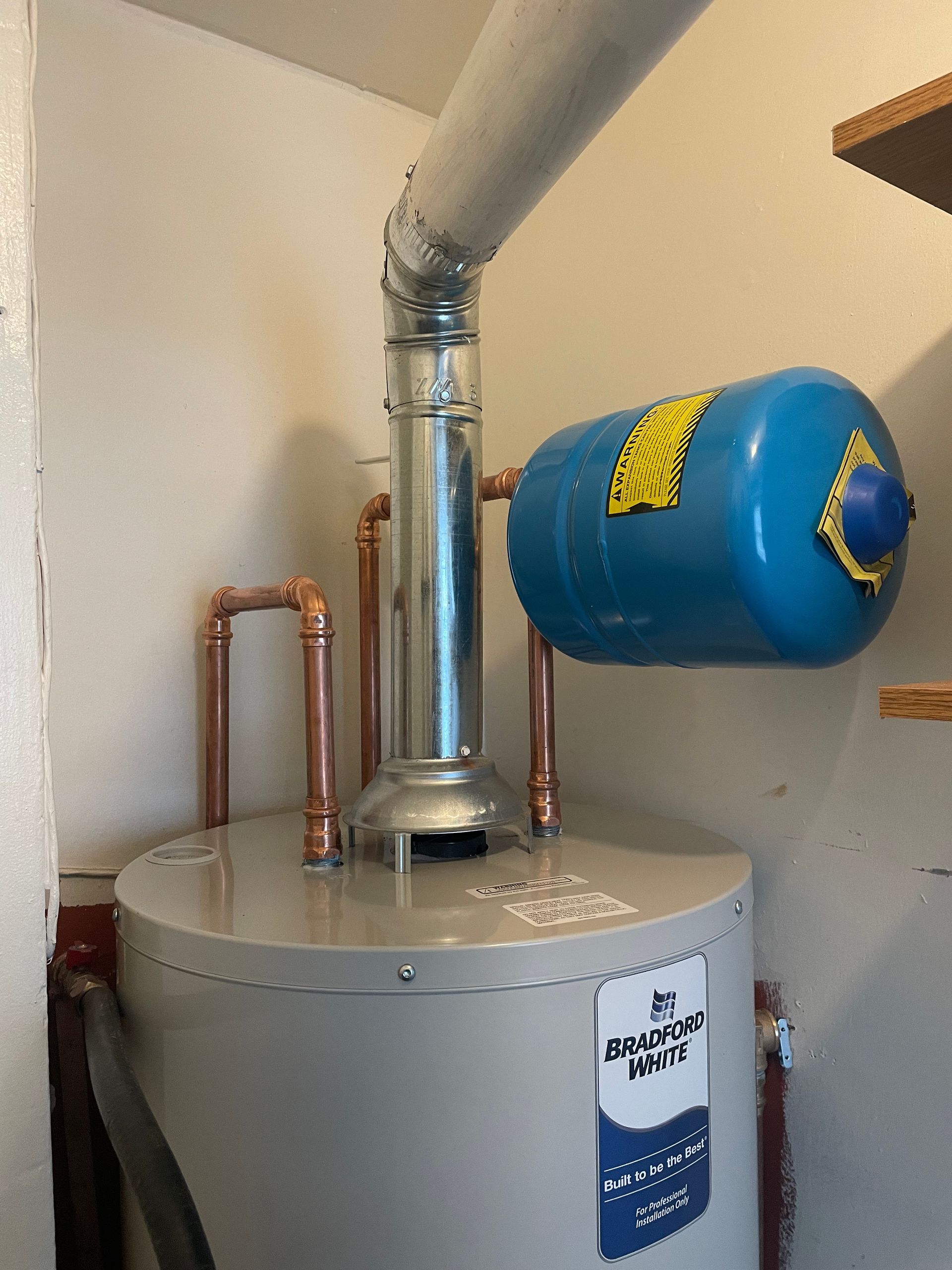 Aqua Plumbing Pros | A water heater is sitting in a closet next to a wall.