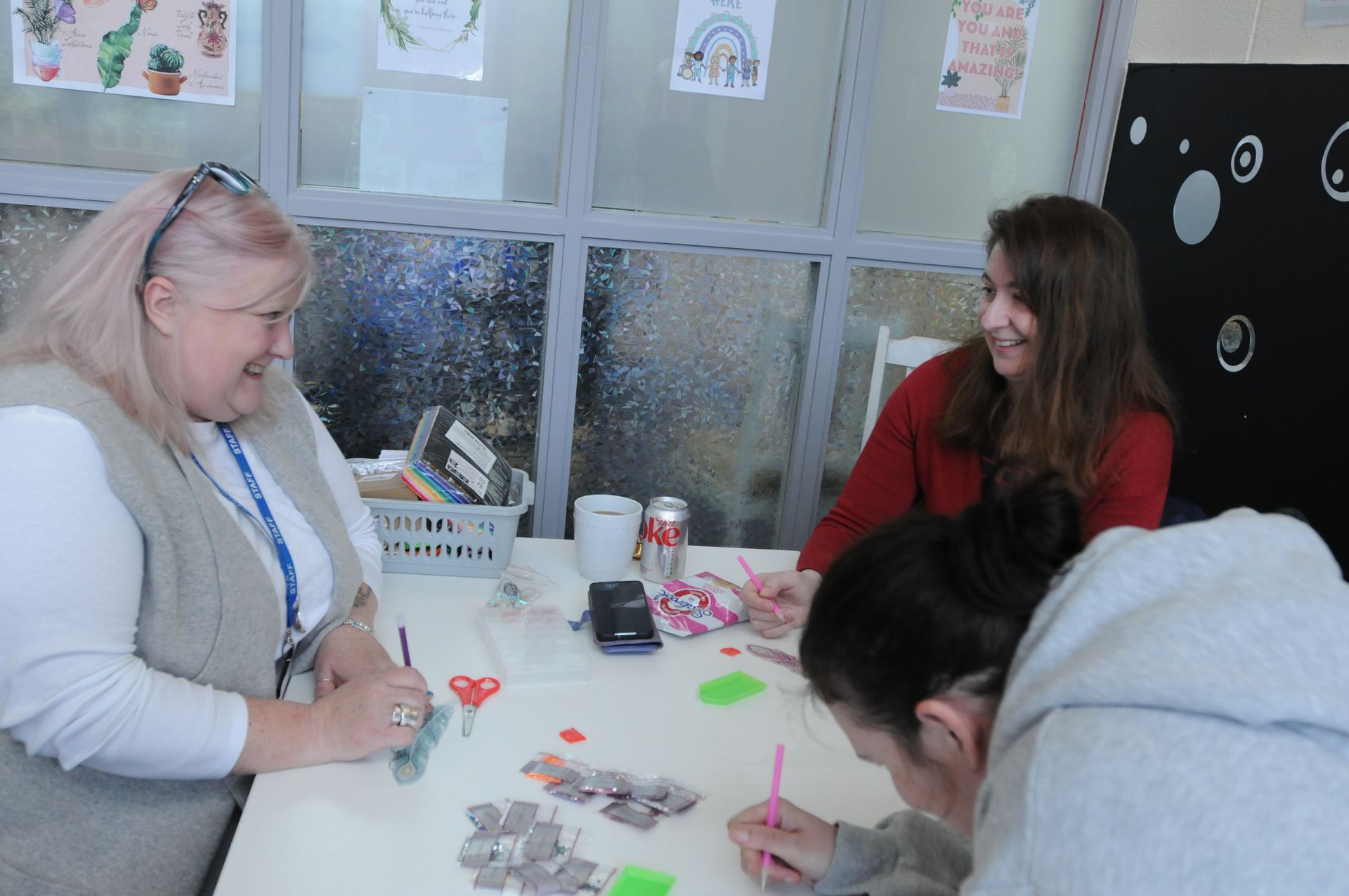 Three ladies sat doing crafts and chatting and smiling