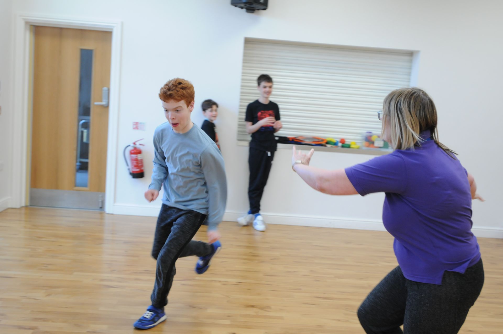 A woman in a purple shirt is teaching a boy how to dance