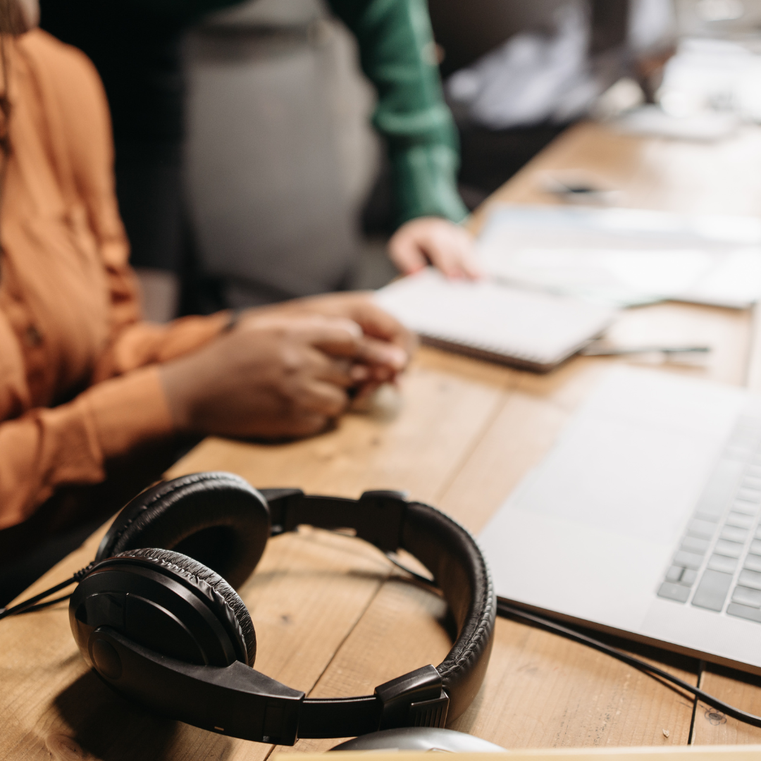 workers sat in a row, close up of a computer and hands and headphones