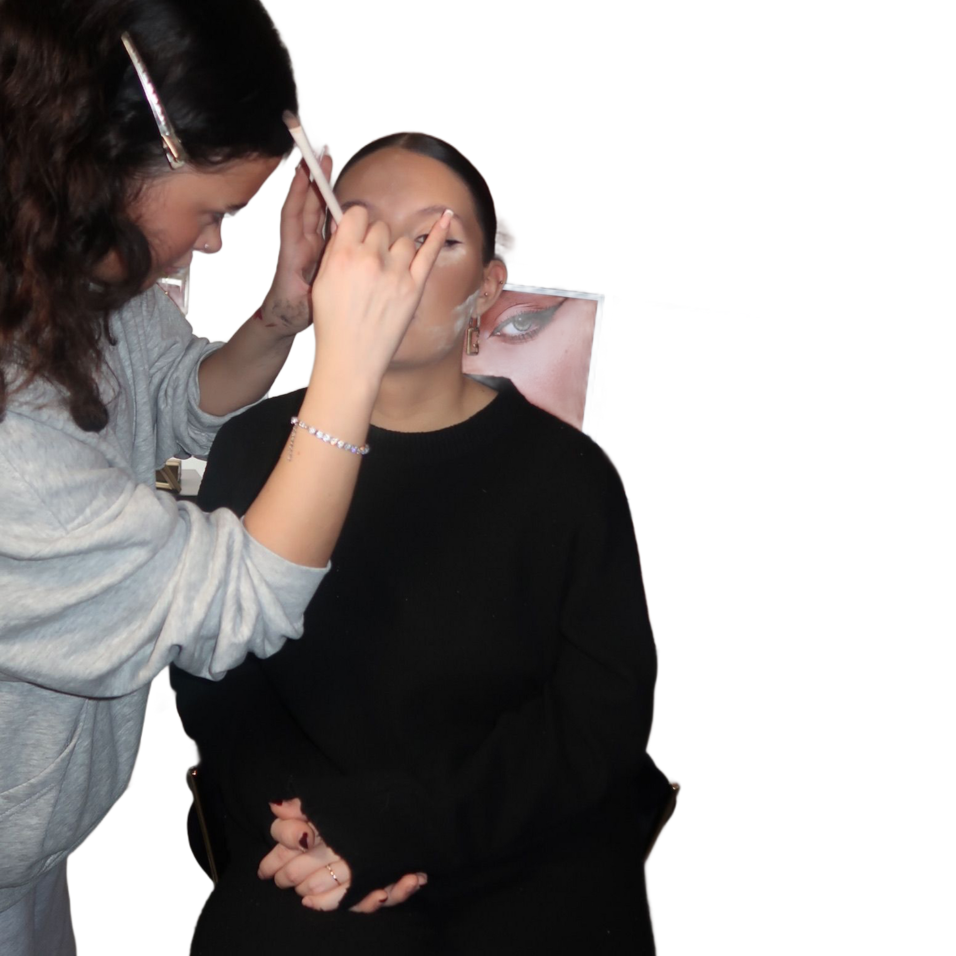 Eine Visagistin schminkt eine Person vor einem Spiegel in einem Studio.