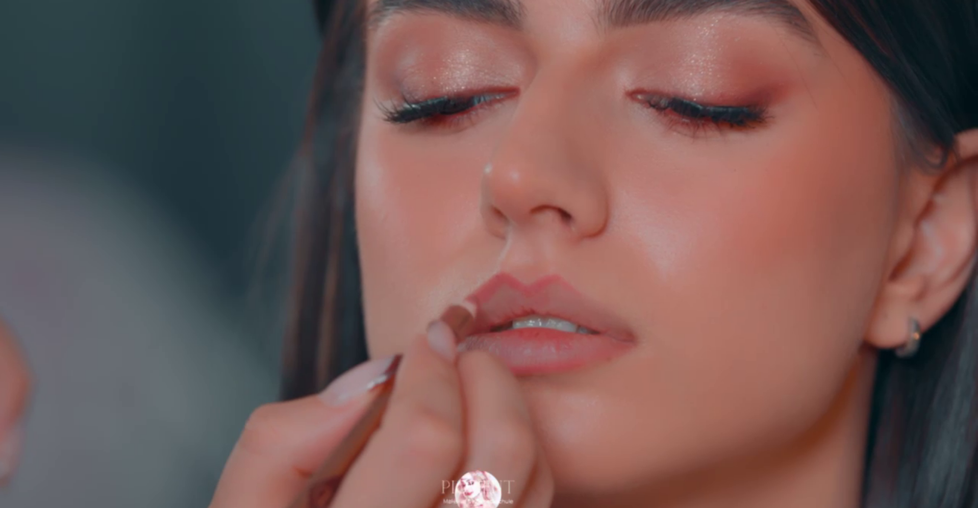 Einer Frau werden von einem Maskenbildner die Lippen bemalt.