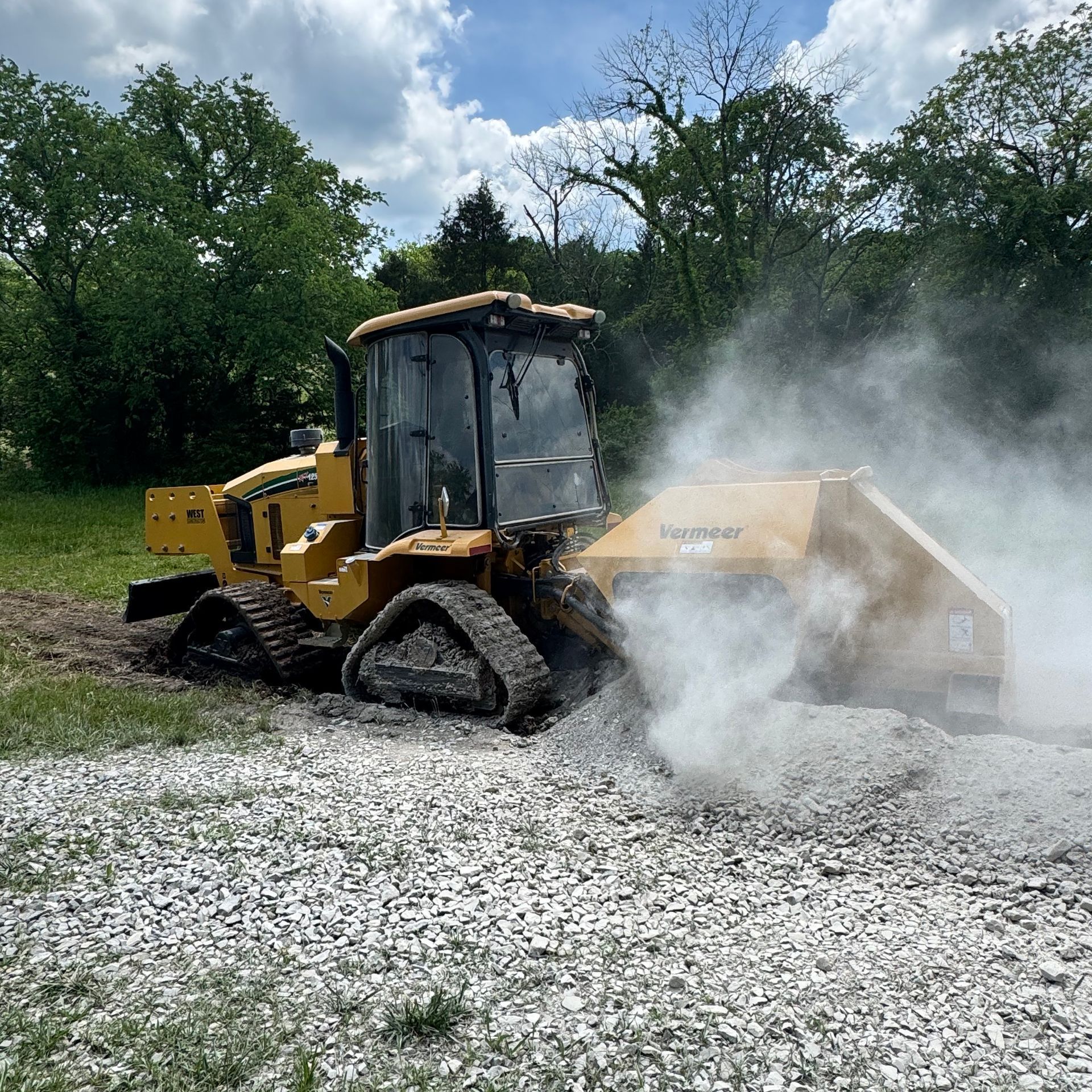 A yellow bulldozer is moving gravel in a field