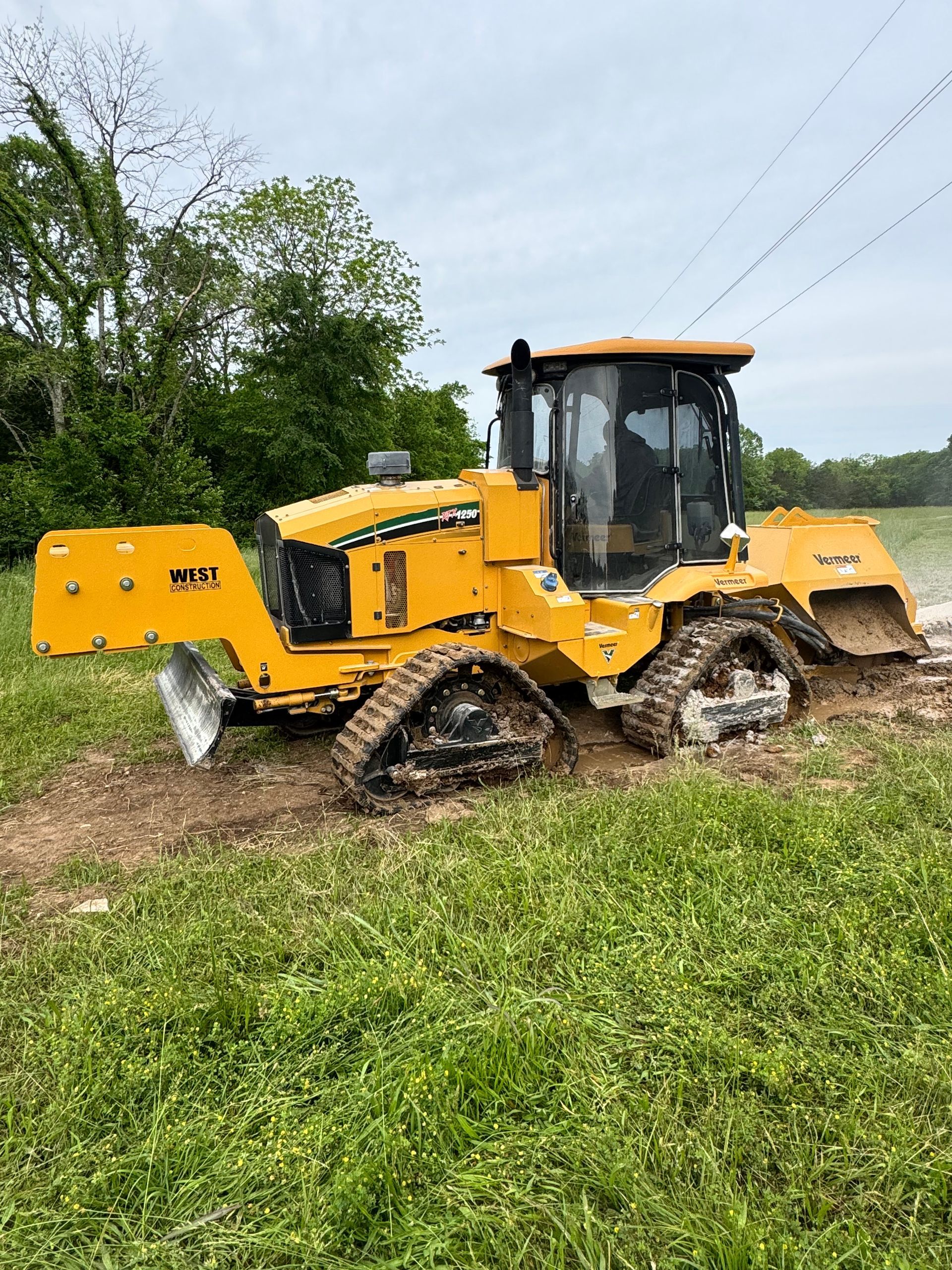 A yellow bulldozer is parked in a grassy field.