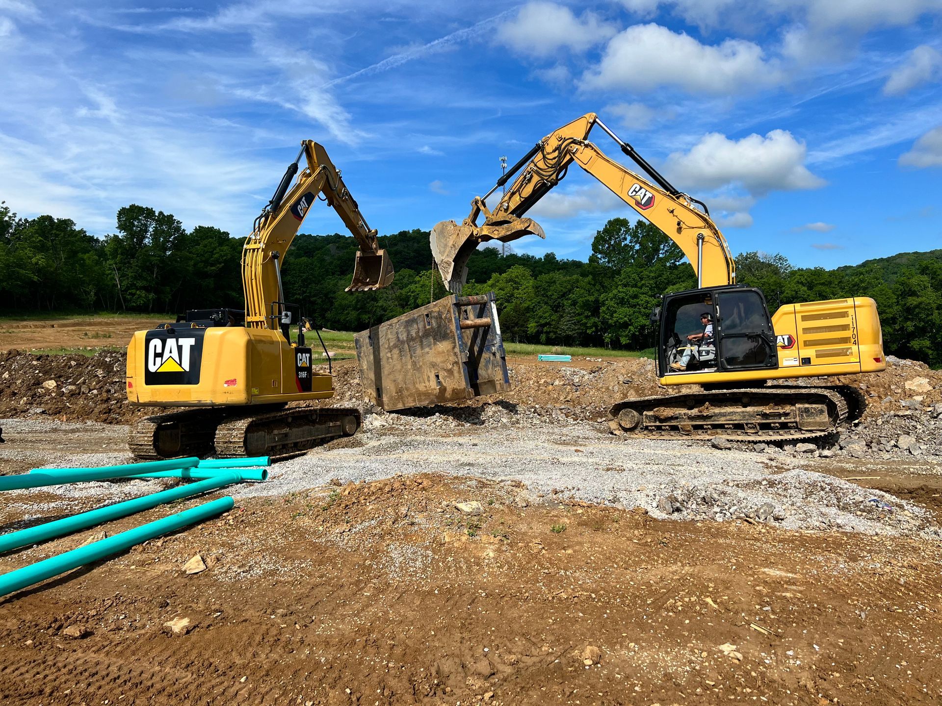 Two cat excavators are working on a construction site.