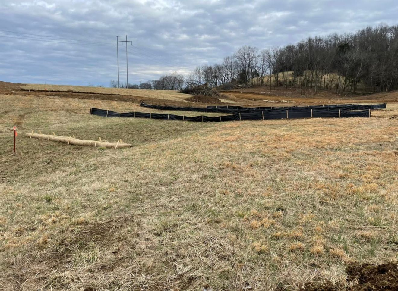 A field with a fence in the middle of it and trees in the background.