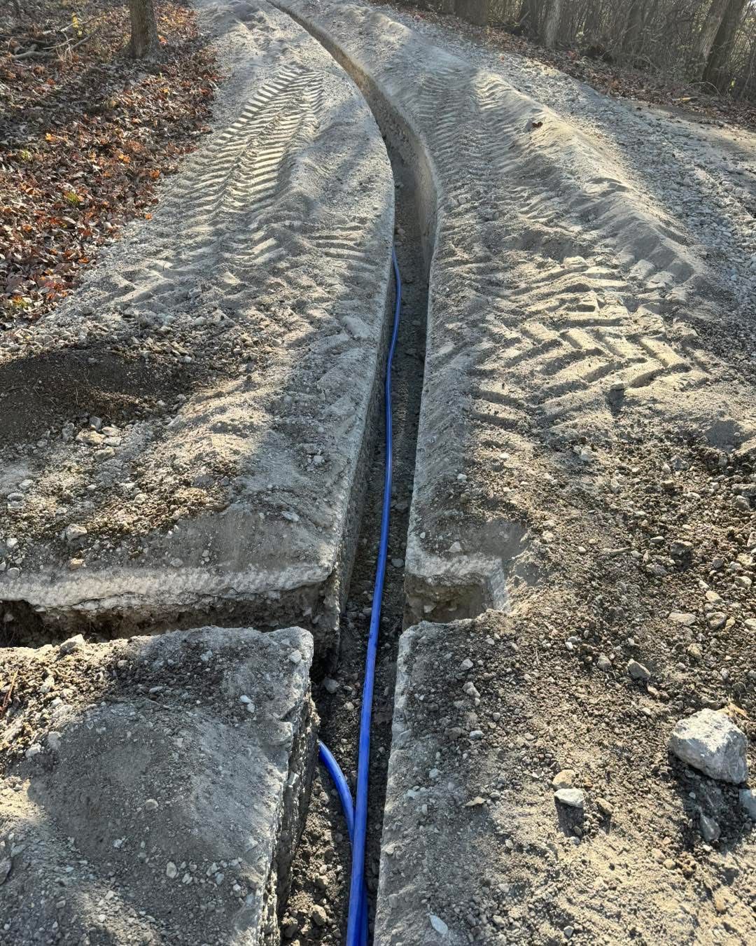 A blue pipe is going through a hole in the ground.