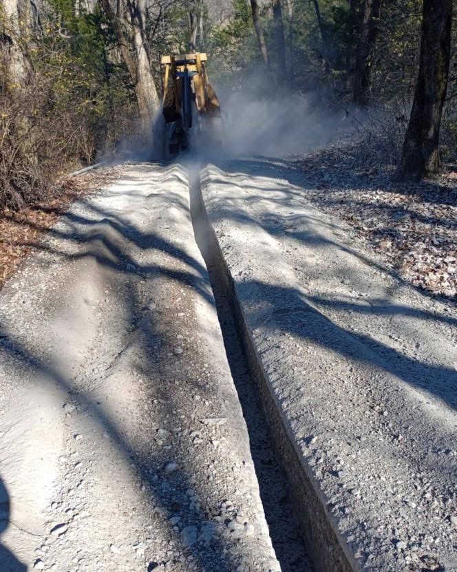 A bulldozer is cutting a hole in the ground on a dirt road.