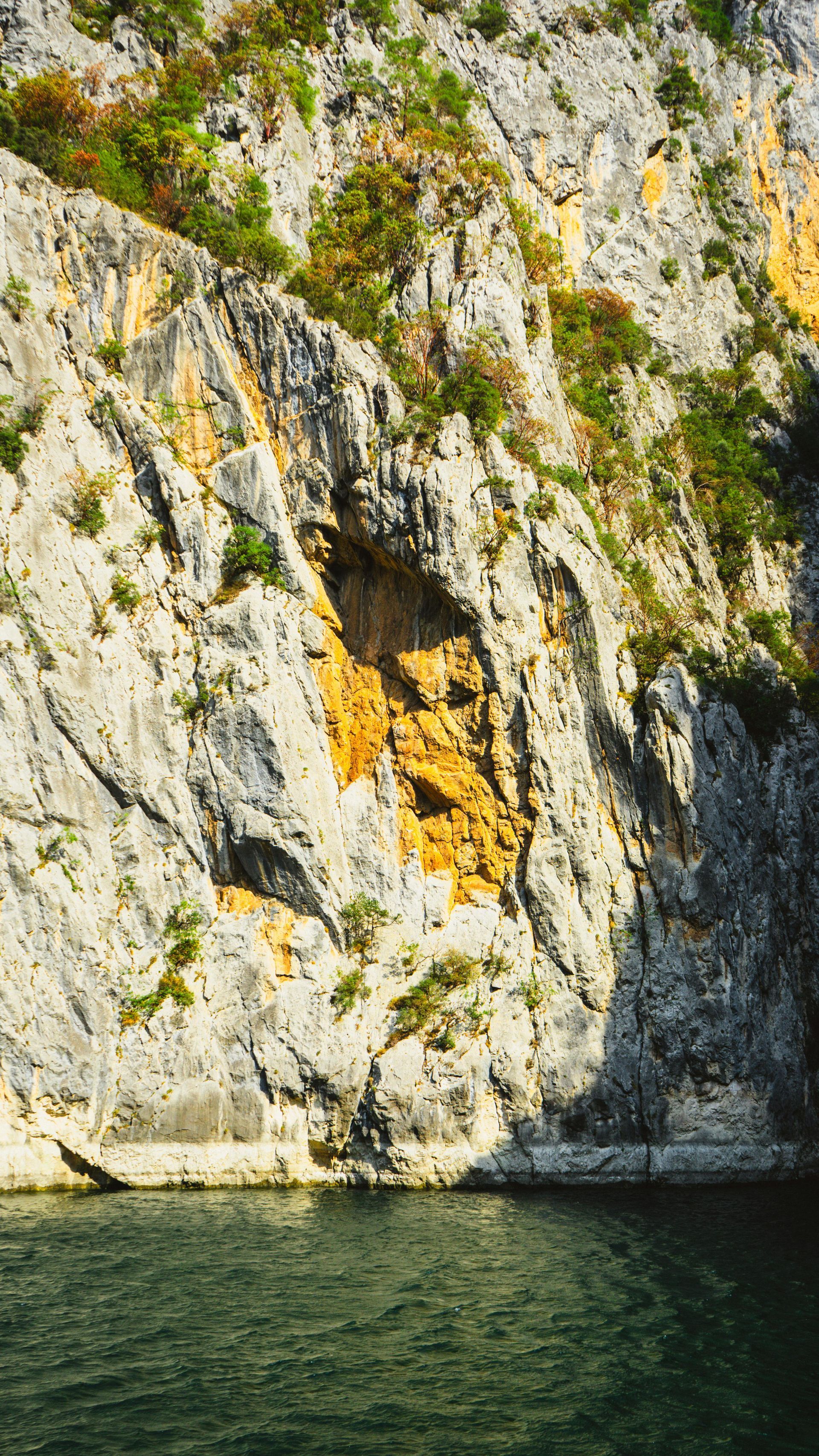 A cliff overlooking a body of water with a cave in it.