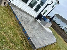 A patio is being built in the backyard of a house.