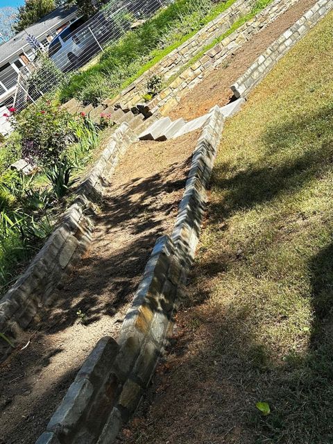 A stone wall is sitting on top of a grassy hill.