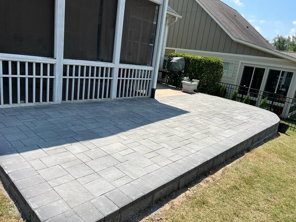 A screened in porch with a patio in front of it.