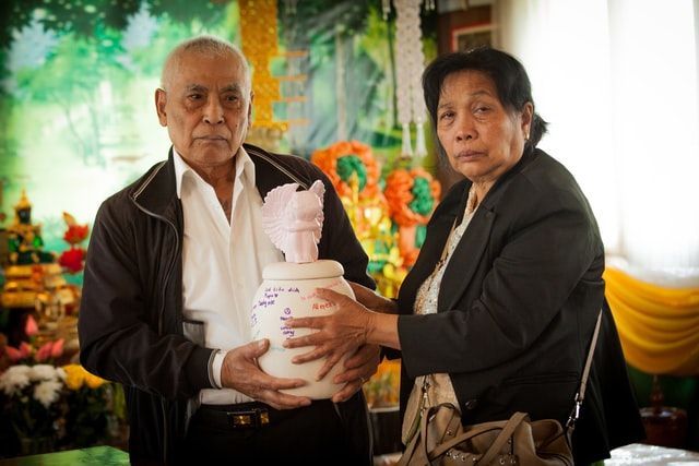 a man and a woman are holding a white urn with chinese writing on it