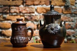 two clay pots are sitting on a wooden table in front of a brick wall .