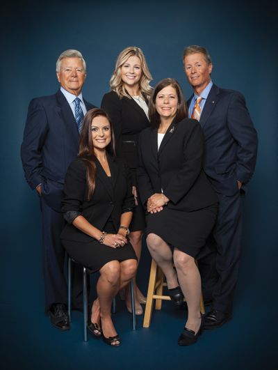 a group of people posing for a picture with one woman sitting on a stool