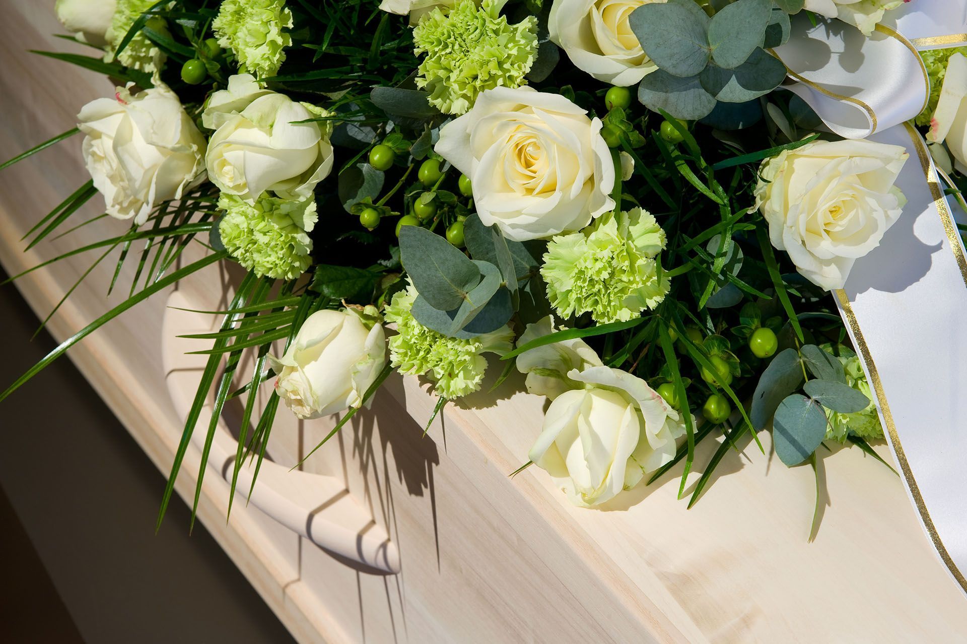 a coffin with white roses and green carnations on it .