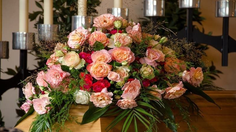 a coffin with flowers and candles on top of it.